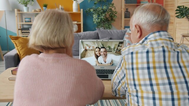Seniorenpaar sitzt vor einem Laptop bei einem Videoanruf